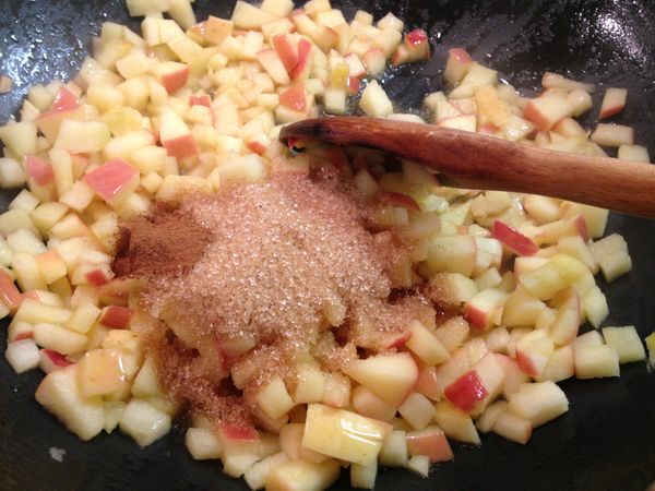 加入黃砂糖、玉桂粉和水繼續拌炒。蘋果於加熱過程中會出水，所以不用擔心太小水分。