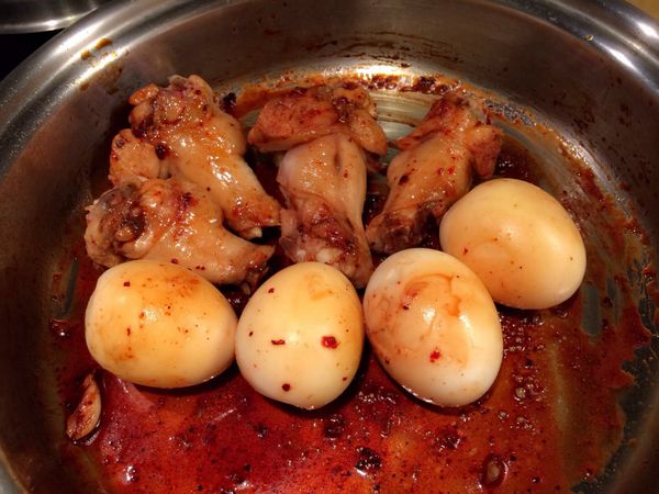 冷鍋加入雞翅、蒜頭以中小火乾煎，雞皮出油後翻面煎至微金黃。加入蛋、醬油、味醂及紅麴醬燒3～5分鐘至上色。