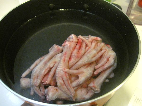 雞腳放在鍋中，冷水淹過雞腳，開火煮沸