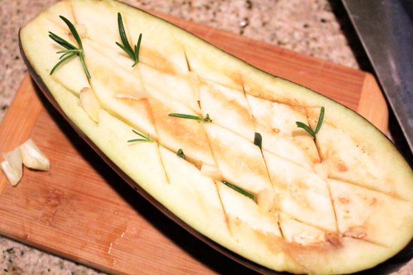 將茄子剖半、於切面處抹大蒜，
再畫十字，將迷迭香、百里香“種”進接縫。