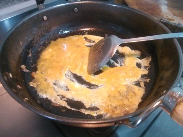 原鍋原油倒入打散的雞蛋，以小火炒至雞蛋都已凝結。(油若是太少，可以再倒入至適當的食用油。)