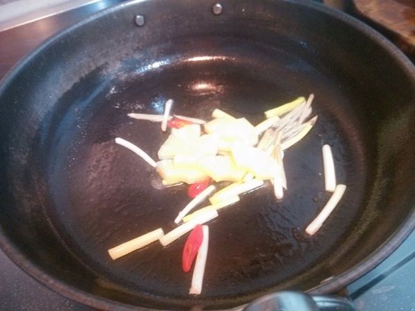 放入鳳梨並且翻炒均勻，加入少許的米酒、白胡椒粉以及適量的清水，然後加入適量的醬油膏，記得一邊加一邊試一下醬汁的鹹度。