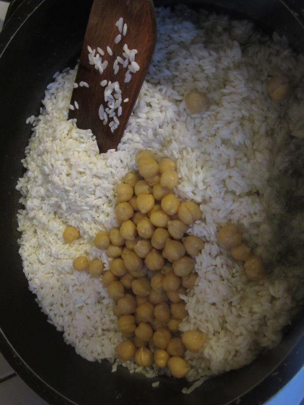 拿出一個寬口的鐵氟龍鍋子，中小火，放入奶油，融化奶油以後放入泡好瀝乾的米和解凍的雞豆一起下去炒。