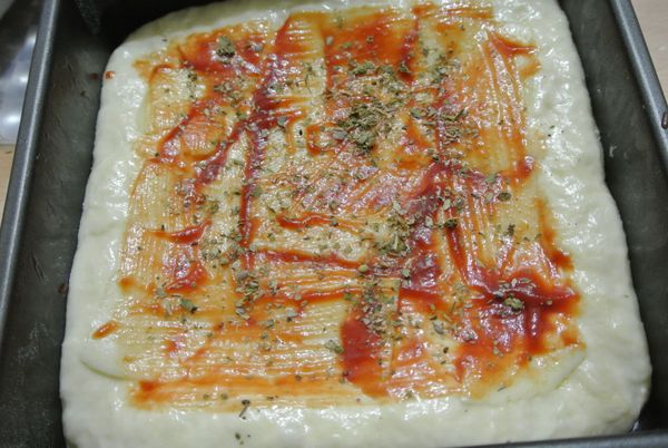 麵團打好，基礎發酵一小時，整形滾圓鬆弛一下，
約30分鐘後可以壓一下麵團中心，手指下去後，可以輕鬆弄出一個洞，麵團也不會回來，這樣比薩麵皮就算發酵完成。
這裡我用方形的氣皿裝麵團，盡量讓麵團撲滿四周，表面刷上番茄醬，撒上義式香料