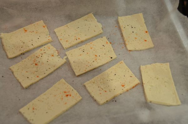 然後將豆腐片排放在已鋪上烘焙紙的微波盤上，並於豆腐表面撒上適量調味料。