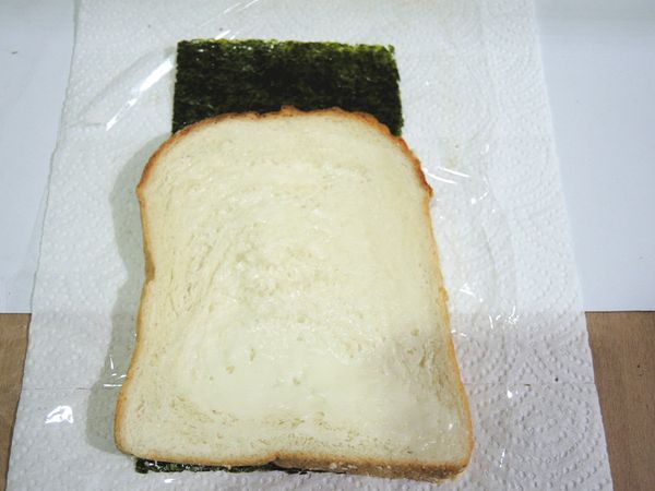 保鮮膜上放一片元本山海苔，土司兩邊都抹少許沙拉醬