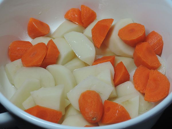 鍋子熱後下2大匙油，加入切塊的馬鈴薯與紅蘿蔔拌炒