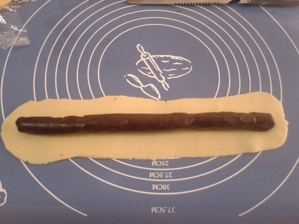 把麵團分成兩份，擀成扁長，中間放上豆沙餡兒。