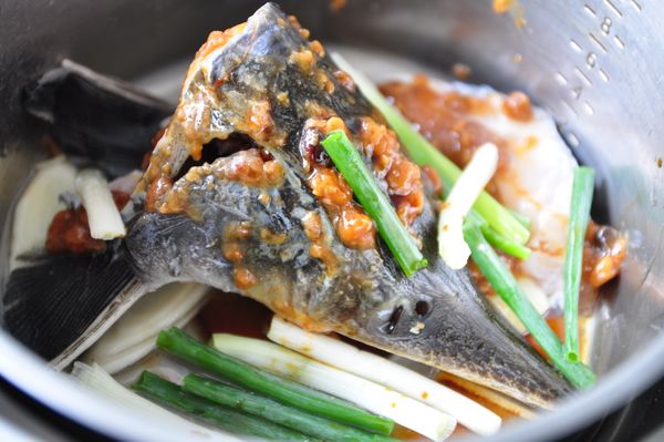 將魚頭放入電鍋內鍋，加入米酒、豆鼓味噌醬、蔥段、薑片，外鍋加入250cc水燉煮即可