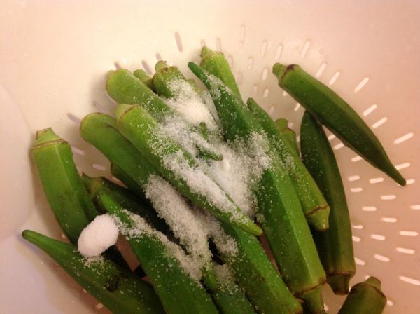 撒1大匙鹽在秋葵上面，用手搓均勻，藉此去除秋葵上的細毛。