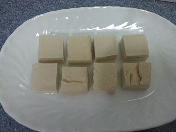 豆腐沖水，切開小塊，倒走多餘水份。