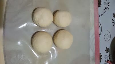 將第一次發酵後麵團取出，分割4份，分別滾圓，蓋上保鮮膜休息15分鐘。