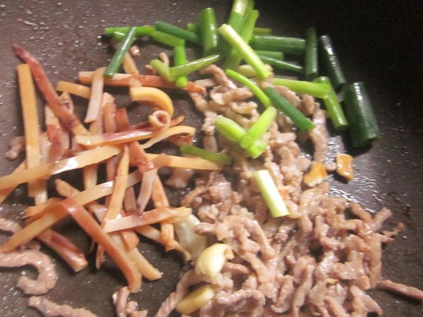 原鍋放入蒜頭.肉絲炒香,續放蔥段.魷魚拌炒