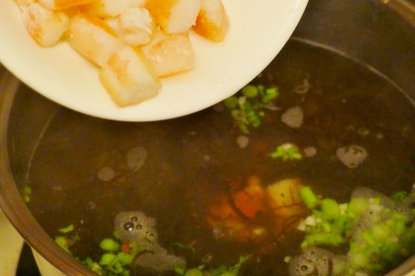 放入香菜莖段、水雲、蟹肉以中大火煮滾，嗆入酒，放進薑泥，倒入醬油、糖、鹽、烏醋[調味]