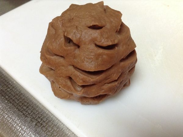 重點3:
把紙模放在砧板的旁邊。（可以馬上放入麵團）。
拿剪刀，由下往上，斜切入麵團中，深到看到內餡。慢慢一層一層向上剪，愈上愈短。
在剪的時候，不要用手去動到麵團，用砧板轉向，一層一層剪。使用砧板的道理在此。