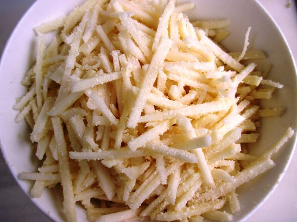 馬鈴薯削皮，切成細絲後，在大碗中混勻起司粉。