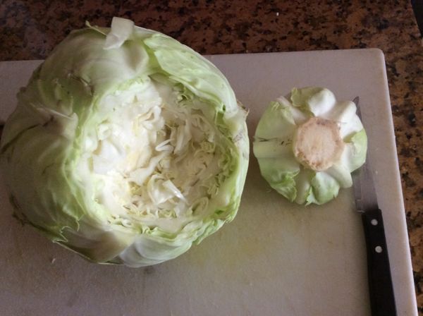包心菜用小刀挖出蒂頭，整顆放入滾水中，並不時淋些熱水在中間，直到能一片片剝開菜葉。