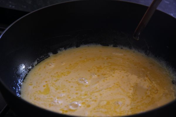 將雞蛋和牛奶混合液徐徐倒入平底鍋中