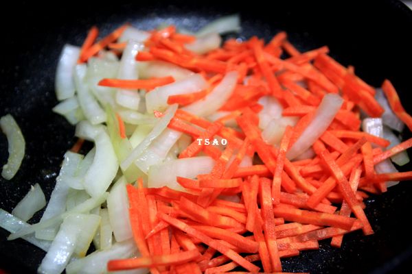 原鍋，使用鍋中的雞油中火炒洋蔥到變軟，再放入紅蘿蔔絲炒一下。