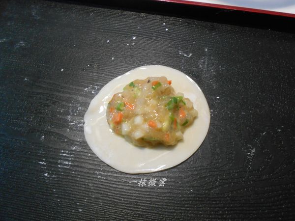 取一片水餃皮週圍抹一點水，舀一小匙內餡放中間