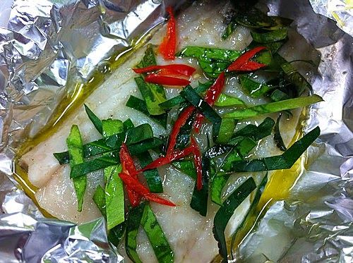 於鱈魚柳上放上檸檬葉、指天椒、魚露及橄欖油。