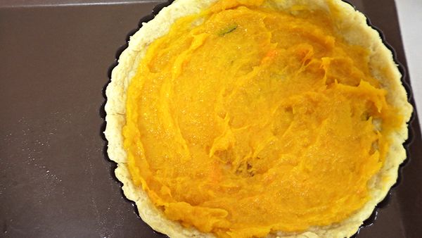 派皮鋪張烤焙紙加入約150g紅豆(任何重物皆可)，入烤箱烤約15分鐘，再將紅豆取出，抹上南瓜泥。