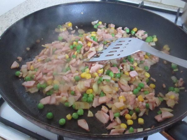 在加入適量的玉米粒、青豆翻炒，和切碎的火腿,加少許的鹽巴調味,,,以小火炒到洋蔥軟熟，