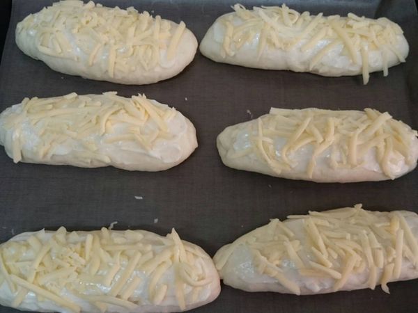 發酵完畢取出，在麵糰表面上塗抹適量的美乃滋，並在其上放乳酪絲，再送進已預熱１８０度Ｃ的烤箱，烤１５分鐘即完成。