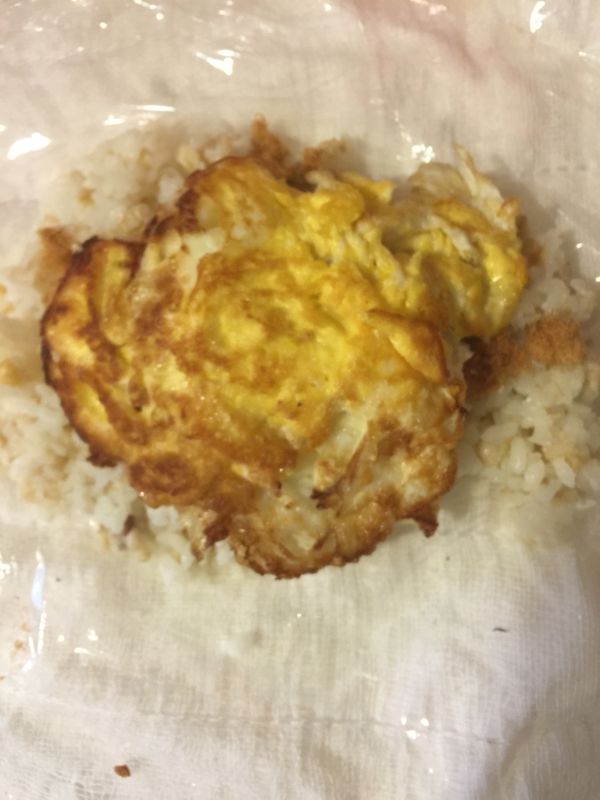 將飯鋪平在保鮮膜上，加入魚鬆，煎蛋，捲成橢圓形就完成了