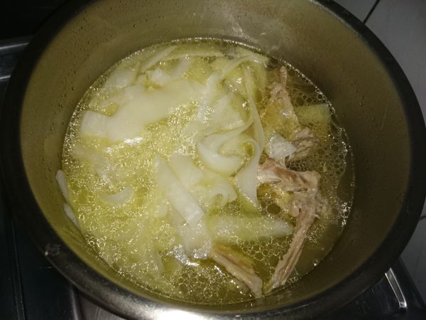 將鴨骨丟回高湯鍋再與蘿蔔片熬煮，