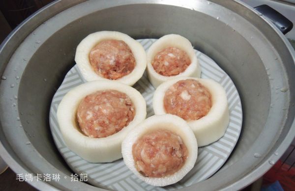 取出豬絞肉在掌心來回甩打幾次使其具黏性後鑲入白蘿蔔，入電鍋蒸煮，約一杯半的水