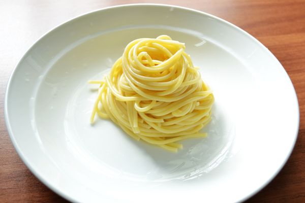 將義大利麵用叉子捲起擺於盤中。