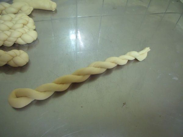 再把兩端用左手捉住,它會旋轉成如圖片的樣子,再把左手食指放在交叉點的中間,右手將麵糰向下搓,使它的扭曲更密。