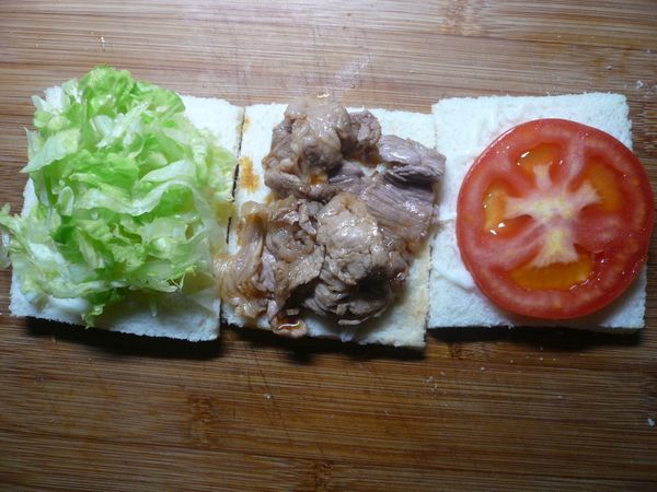 在每一片土司上排上不同的食材，一片放萵苣絲、一片放拌過穀盛壽喜燒醬的豬肉薄片，一片放上蕃茄片。