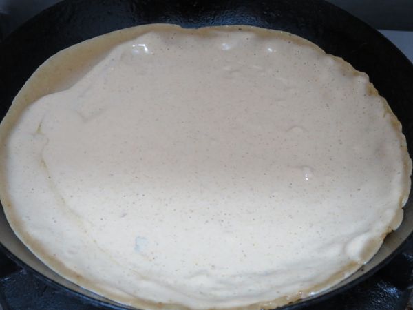鍋裡抹一層薄油，放一半麵粉糊，轉動鍋子讓麵粉糊更均勻且更圓。