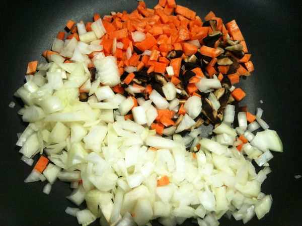 取出平底鍋，倒入少許苦茶油（或其他耐高溫的油品也可以），放入步驟3的香菇碎、洋蔥碎、紅蘿蔔碎，拌炒。