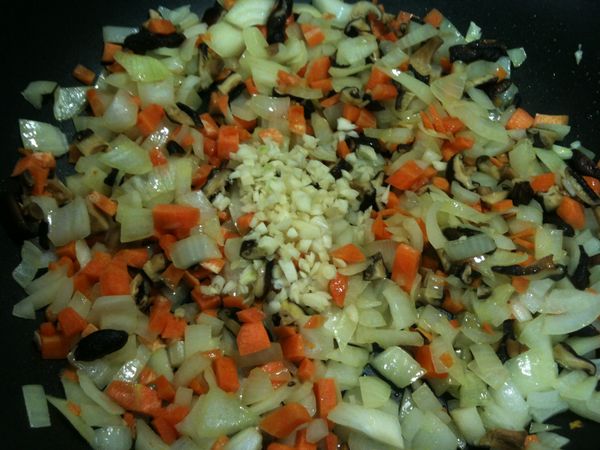 待聞到香菇、洋蔥和紅蘿蔔的香氣後，放入步驟3的蒜頭碎，拌炒（蒜頭較易熟，且炒過頭會有苦味，所以炒完香菇碎、洋蔥碎和紅蘿蔔碎後，再加進拌炒，才可以享受蒜頭最棒的香氣。）。