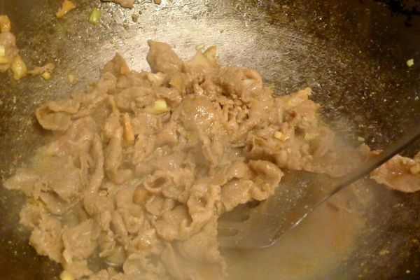 熱鍋，倒些許油，加進蒜、蔥白[爆香料]爆香，再放入步驟2醃漬過的肉片翻炒至肉色變白