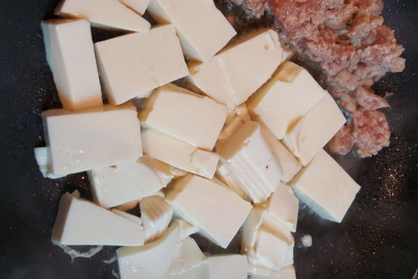 熱鍋，放1T蔬菜油，把豬絞肉炒至變白色，推到鍋子旁邊，把川燙好的豆腐放入鍋中，煎至微黃色，