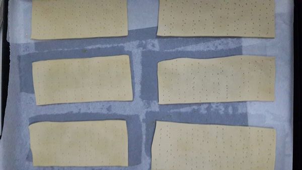 將派皮放至烤盤上，並用叉子戳上小洞，以免派皮膨脹，在派皮上再舖上一張烤盤紙（要大於烤盤尺寸）。