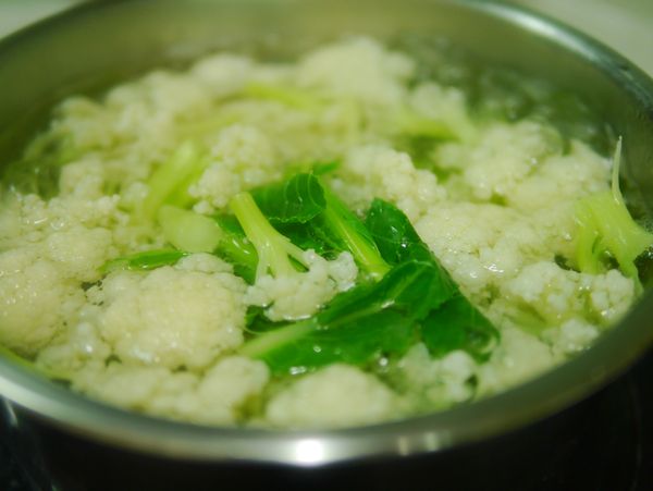 白花椰菜洗淨、切小塊，放加鹽的滾水中汆燙2.5~3分鐘，撈起沖冷水。這時可再用蒜頭、火腿丁一起炒香備用。