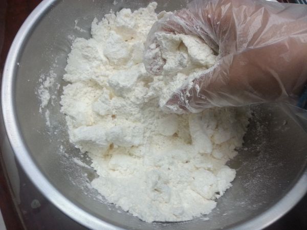 用叉子將所有粉類拌勻後，丟入切成小塊的奶油，用手指搓揉，直到奶油與麵粉結合成為均勻無顆粒的黃色粉末。