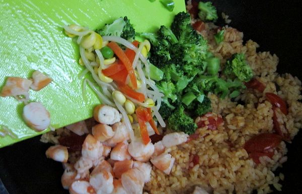 確定飯的顏色差不多均勻後，就可以把備用的蝦丁及蔬菜通通倒入。