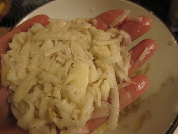 用指尖抓一把馬鈴薯絲，先捏成球狀後，壓扁。