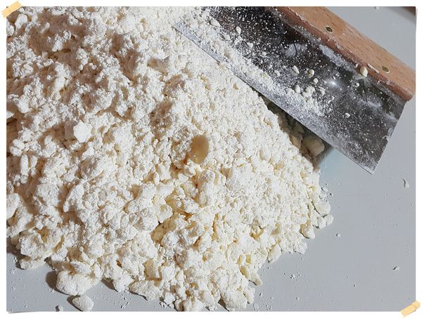 雙手用像在玩沙子的方式搓洗.混合成砂粒狀.拿刮刀把底部的麵粉翻上來,用刮刀切拌,形成粉包油的狀態(有些大顆粒奶油沒關係.不用全部很細,這就是千層成功的關鍵)