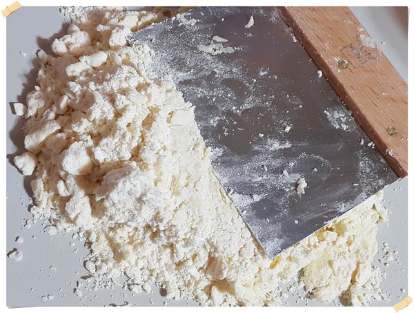 分次加入冰水(一定要冰水~一定要冰水~一定要冰水~因為很重要所以說三次)拿刮刀把底部的麵粉翻上來,用刮板以按壓的方式混合,絕對不要去搓揉麵團