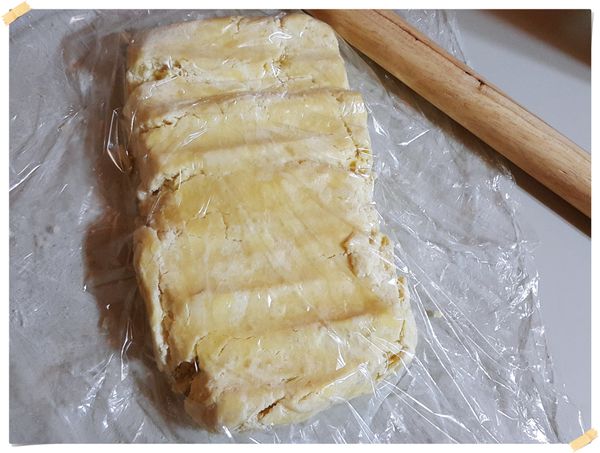 取出冰硬的麵團,上面再蓋一張保鮮膜,用擀麵棍用壓的方式伸展開來,再轉90度一樣用擀麵棍用壓的方式伸展開,然後再橄成厚薄一致的長方形