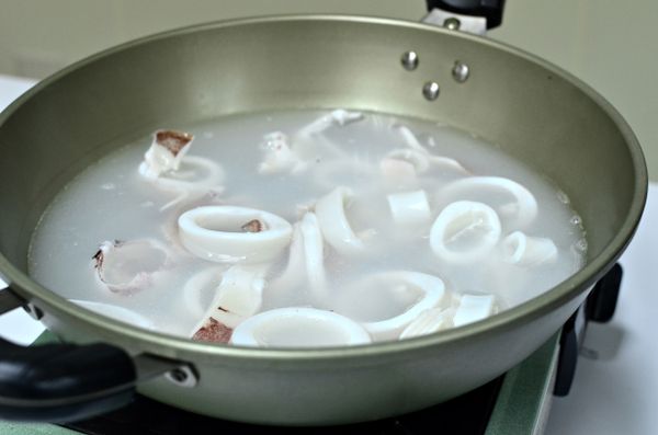 將中卷內臟拉除、洗淨（不剖開），撕去外膜，橫切成小圓圈狀，放入開水中快速汆燙過撈出。