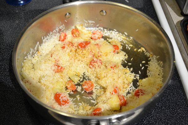 等到番茄出水，把洗好的米放入一起炒，炒到半透明的白米變成白色