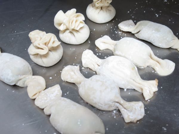 餃皮邊邊塗上一層薄水，餃皮卷起。做出糖果造型或其他造型。餃皮交接處朝下。